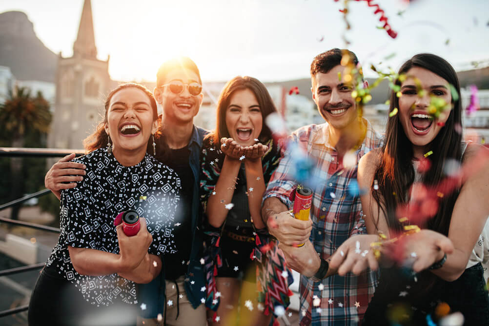  A group of friends celebrating a EuroMillions win with confetti on a rooftop