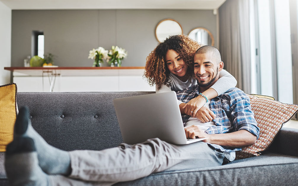 Couple celebrating a lottery win after checking results on a laptop